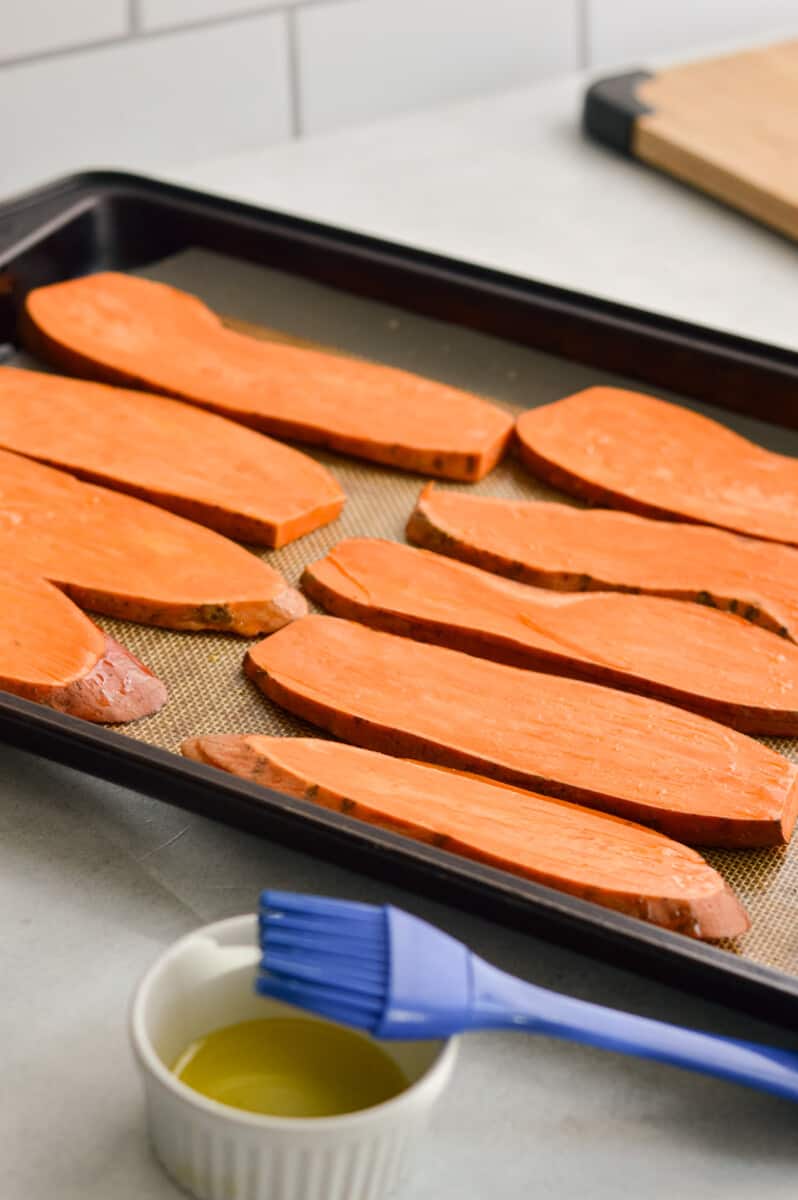 Brushing sweet potato slices with oil.