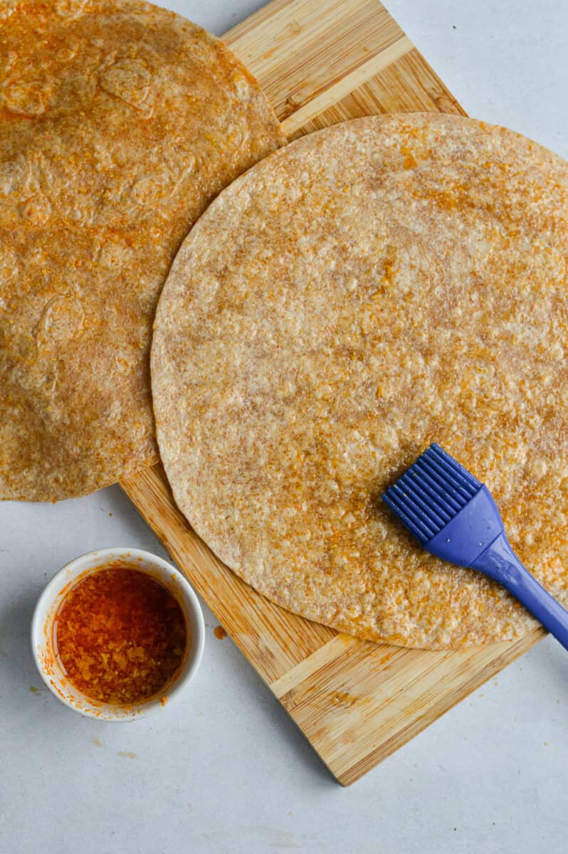 Brushing a whole wheat tortilla with olive oil.