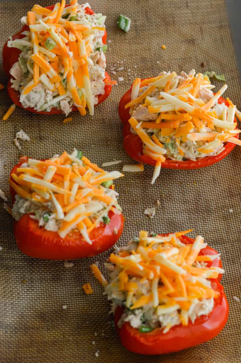 Adding shredded cheese on stuffed red peppers.