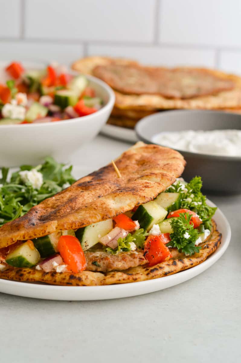 Close up of folded Greek smashed turkey burger pita, filled with Greek salad.
