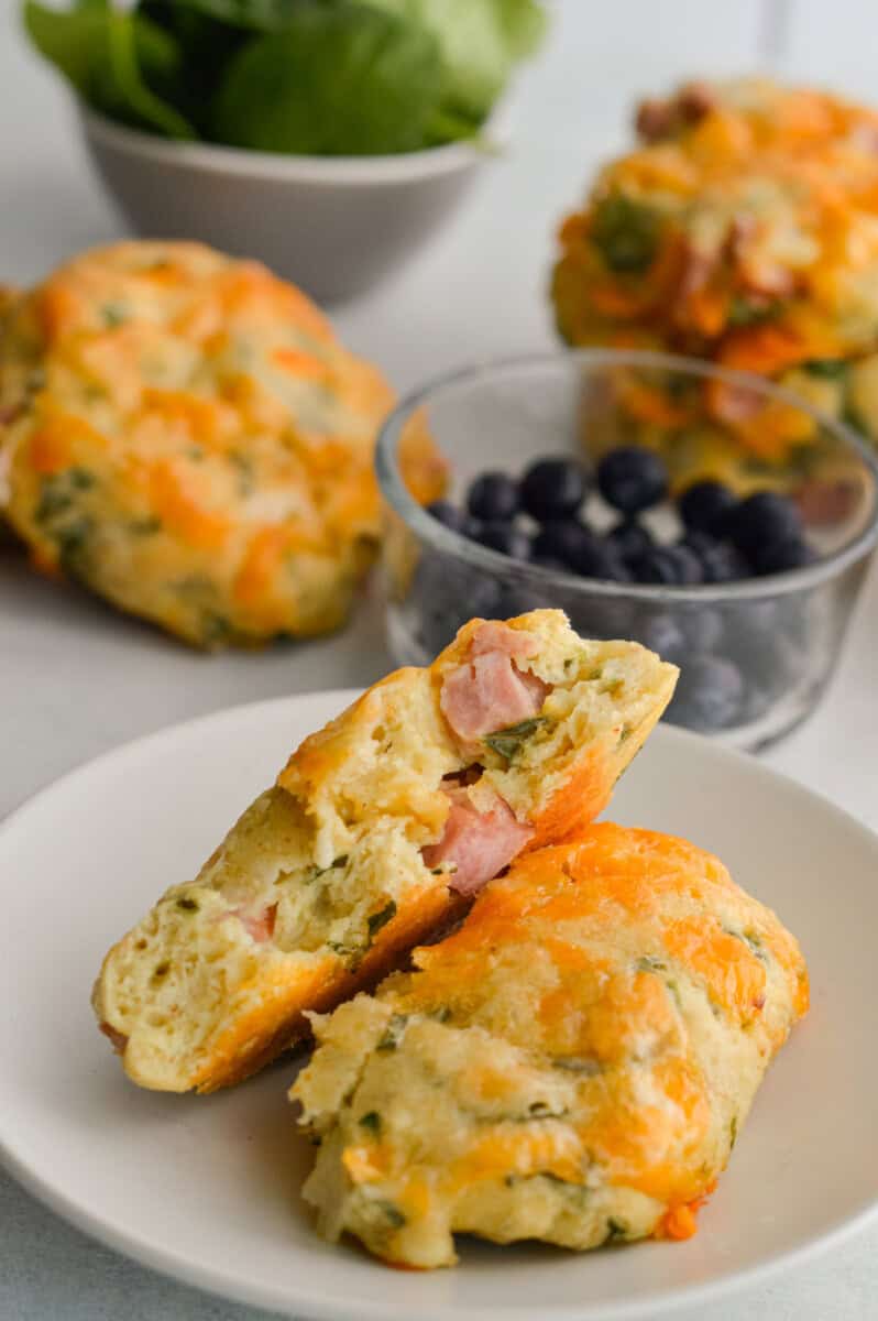 Two protein biscuits on a plate with bowl of blueberries in the background.