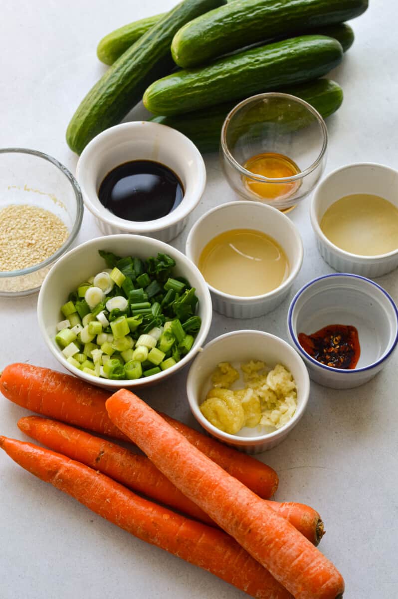 Ingredients including carrots, cucumber, green onion, garlic, soy sauce, honey, chili oil, sesame oil, rice vinegar, ginger and sesame seeds.