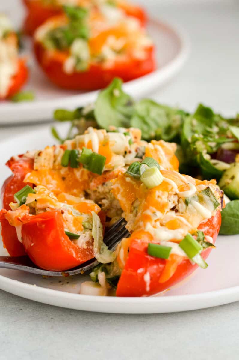 Cutting open a tuna stuffed red bell pepper with a fork.