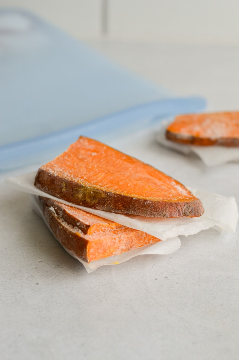 Storing sweet potato toast slices in a freezers safe bag with parchment paper between slices.