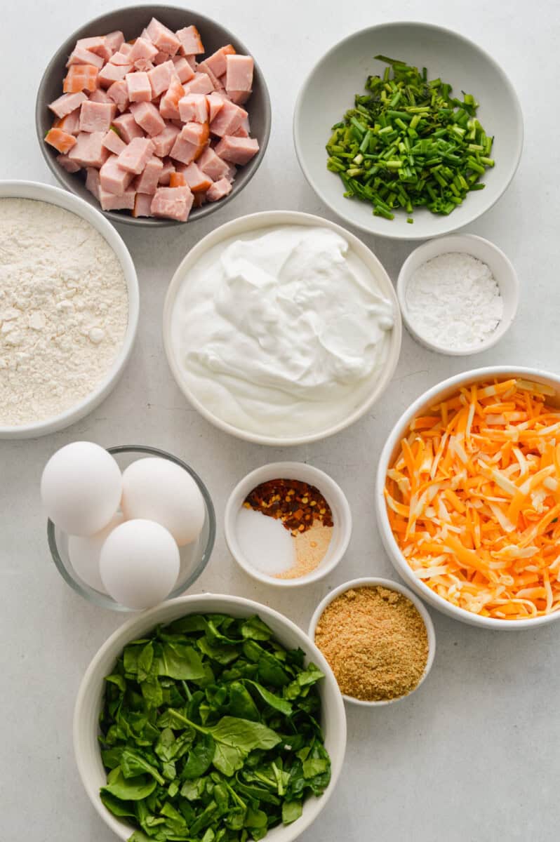 Ingredients including eggs, diced ham, cheese, Greek yogurt, chives, flour, spices, spinach and flaxseed.