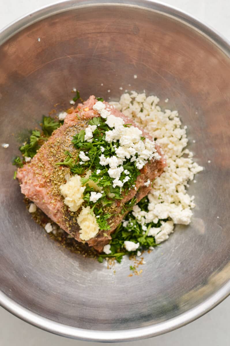 In a large mixing bowl, mixing olive oil, ground turkey, salt, garlic, oregano, black pepper, cumin, parsley and feta. 

