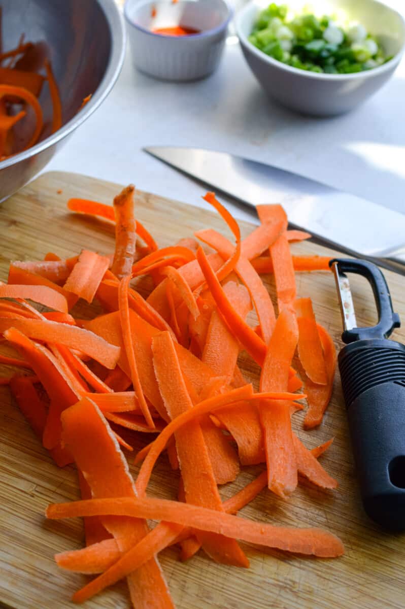 Shredding carrots into ribbons with a vegetable peeler.