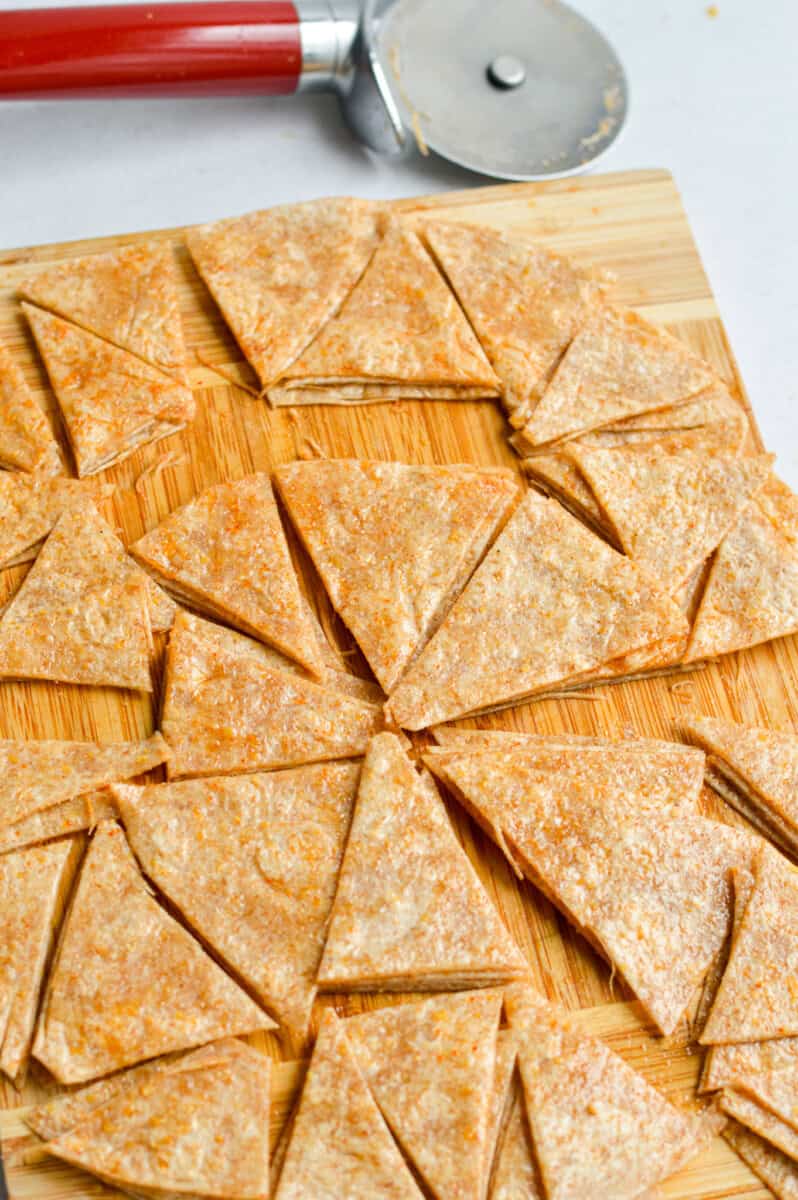 Slicing tortilla into triangular chip shapes.