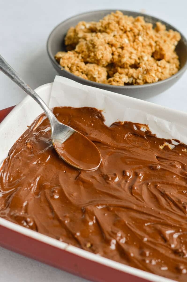 Spreading melted chocolate onto oat mixture.
