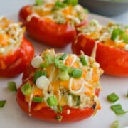 Plate of buffalo ranch tuna stuffed red peppers with cheese and green onions on top.