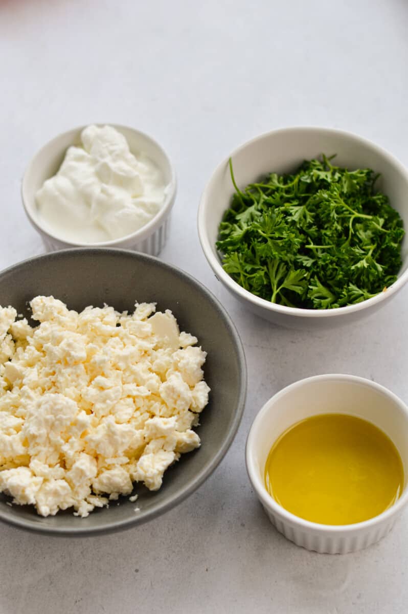 Ingredients including feta cheese, Greek yogurt, lemon juice, parsley and olive oil. 