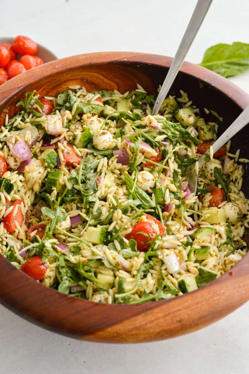 Wooden bowl with mixed orzo pesto salad.