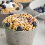 Jar of blueberry crumble overnight oats topped with granola and berries.
