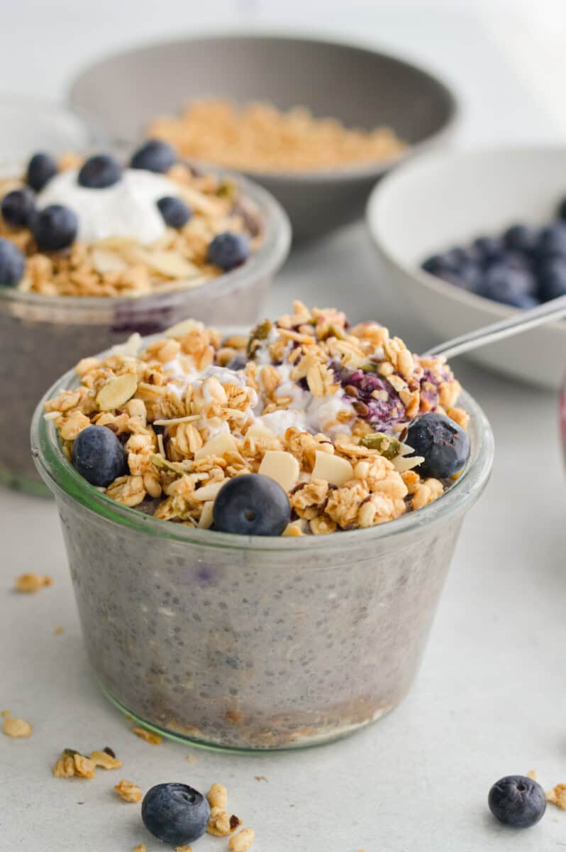 Jar of blueberry crumble overnight oats topped with granola and berries.