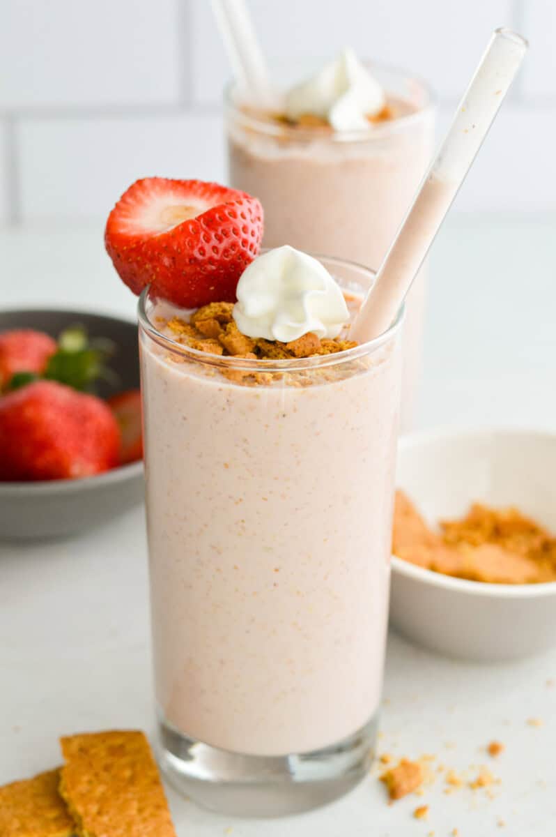 Glass of cheesecake cottage cheese smoothie with graham crumbs, whipped cream and a strawberry.