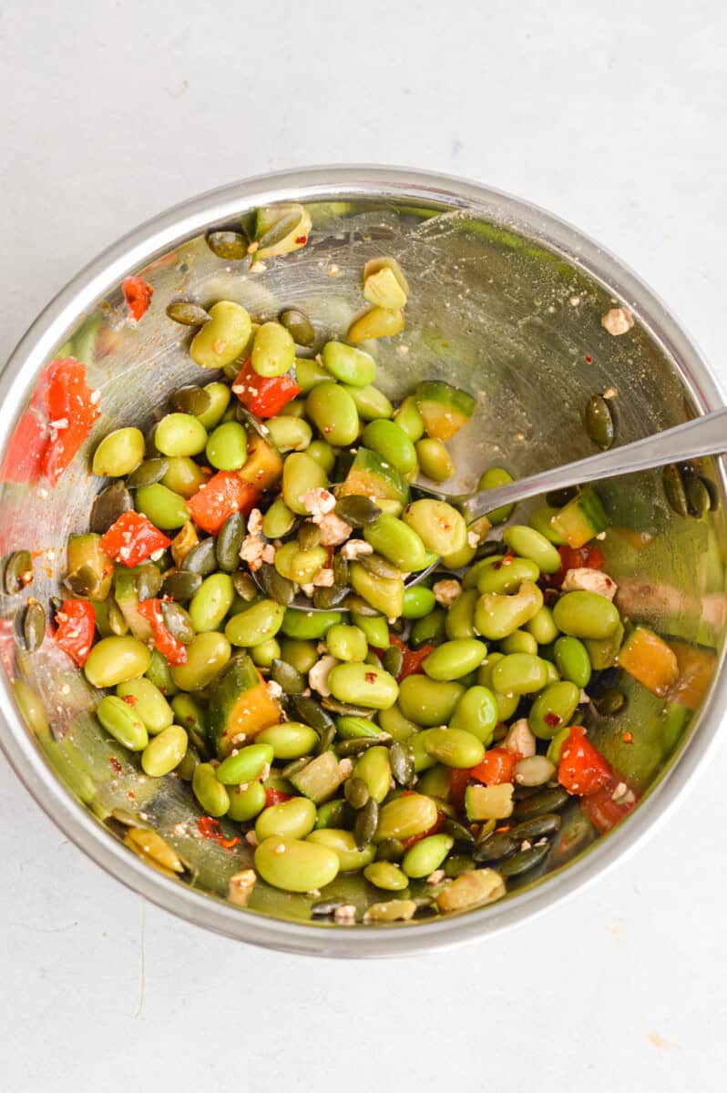 Making edamame cucumber salad in metal mixing bowl.