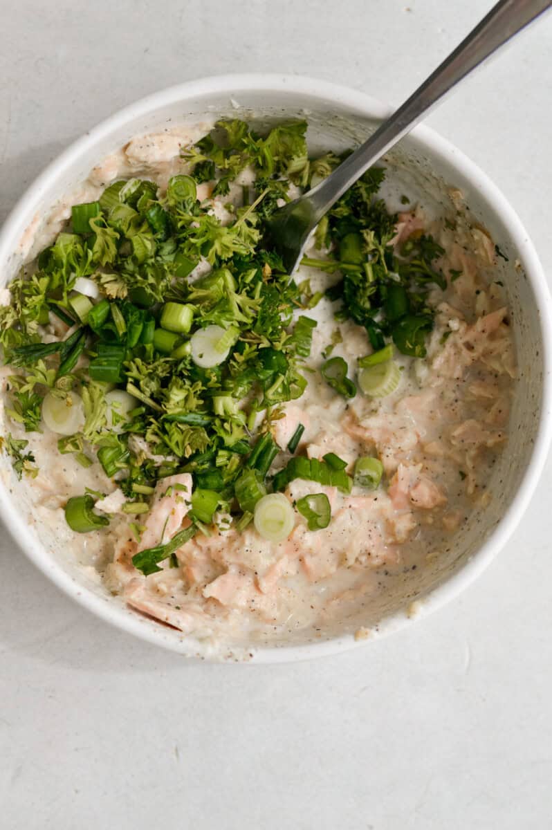 Adding herbs and chives to tuna dip.