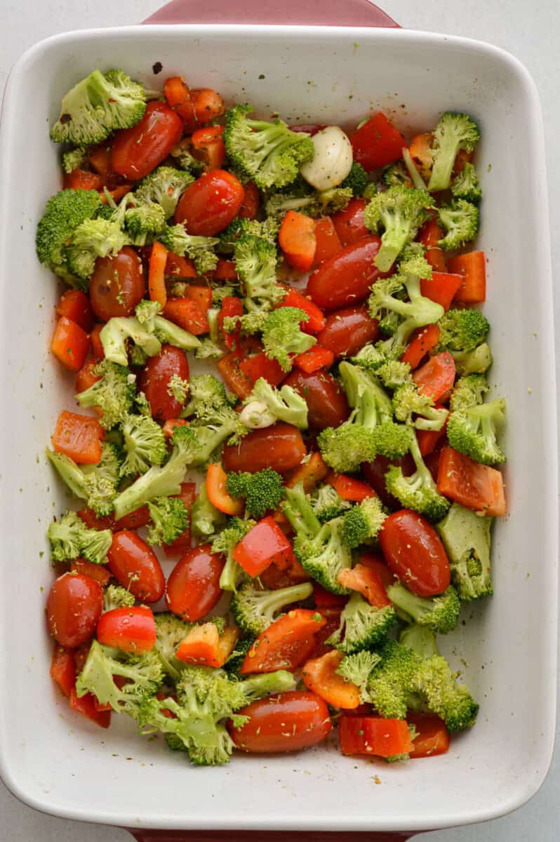 Adding cherry tomatoes, broccoli and red peppers to a tray.