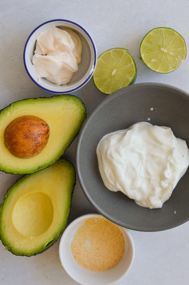 Ingredients including avocado, greek yogurt, lime, mayo and seasoning.
