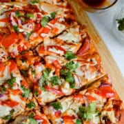 BBQ chicken flatbread served with a side of BBQ sauce.