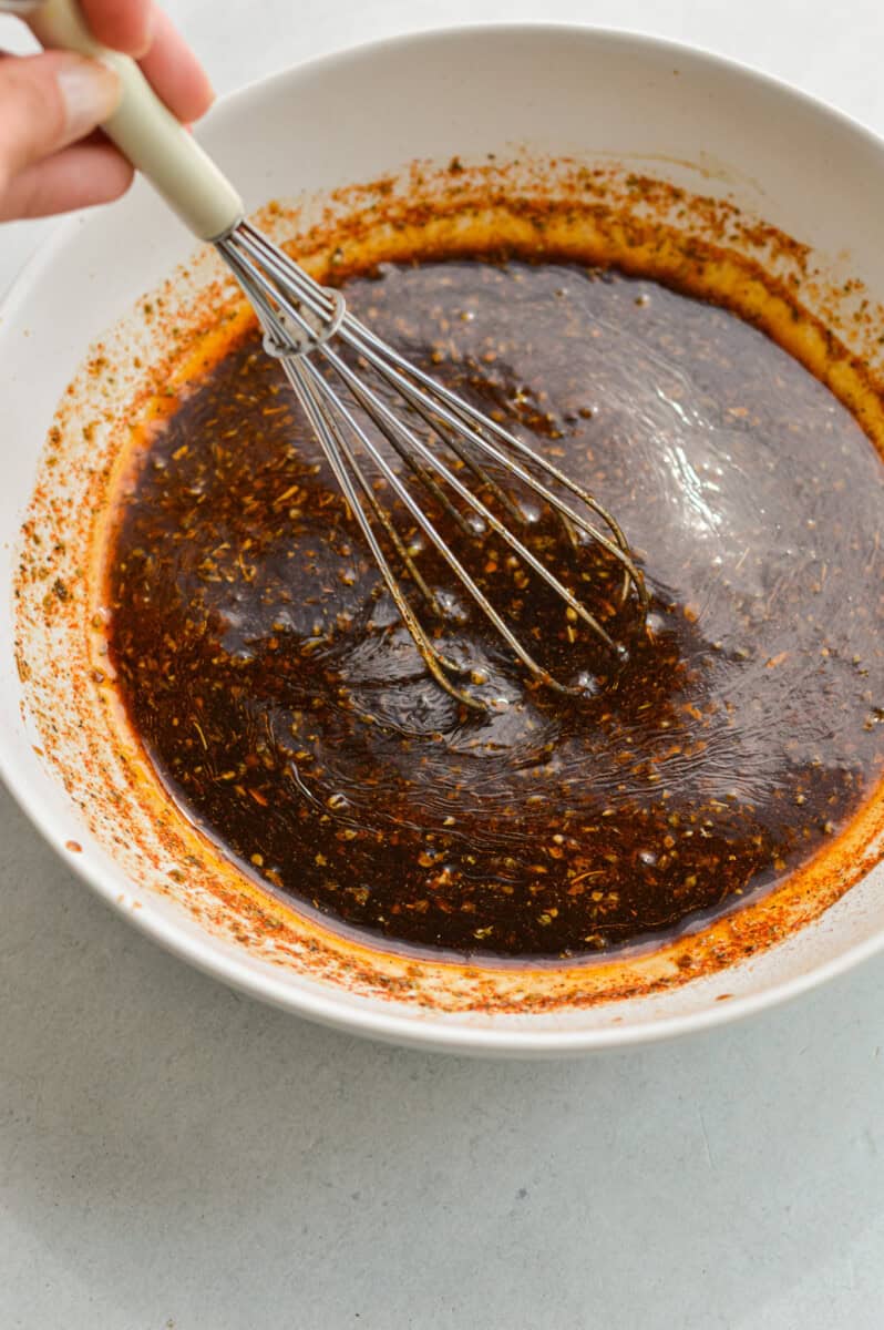 Whisking together marinade with  orange juice, soy sauce, honey, olive oil, pressed garlic, dried oregano, black pepper and paprika.