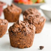 Chocolate baked oat cups with strawberries in the background.