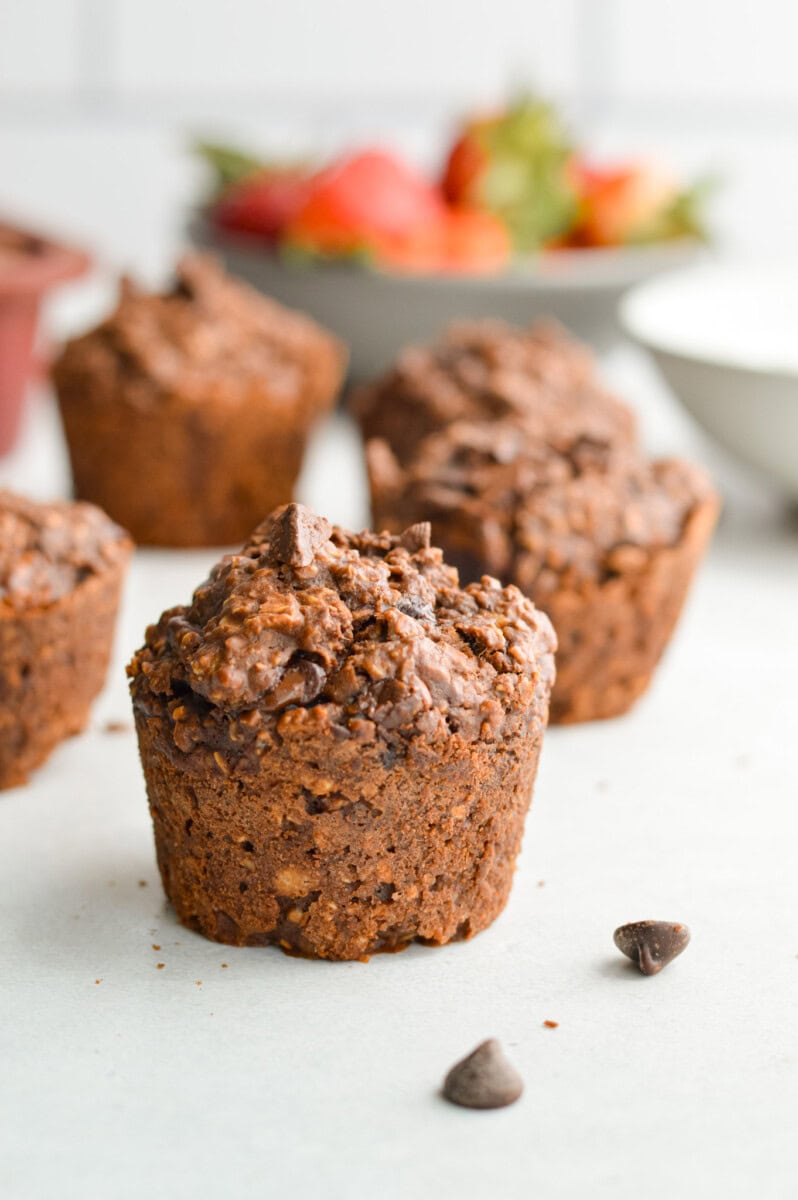 Chocolate baked oat cups with strawberries in the background.