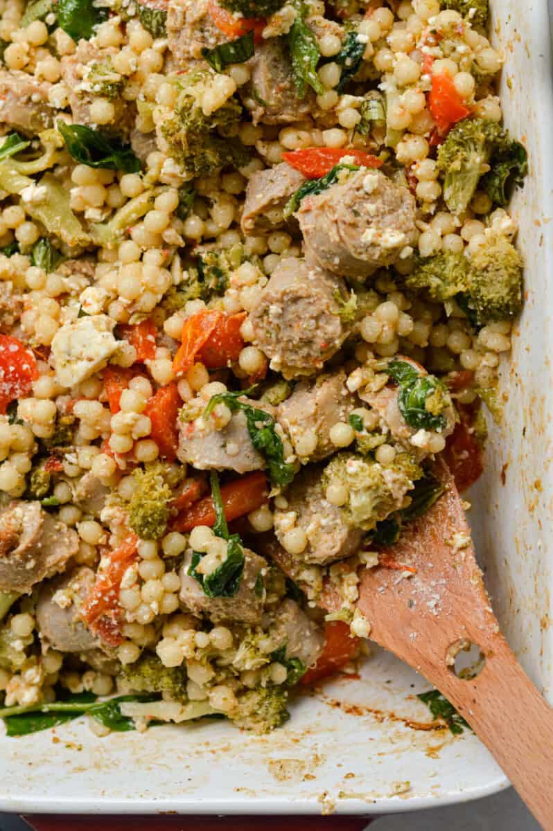 Mixing baked feta and sausage couscous.