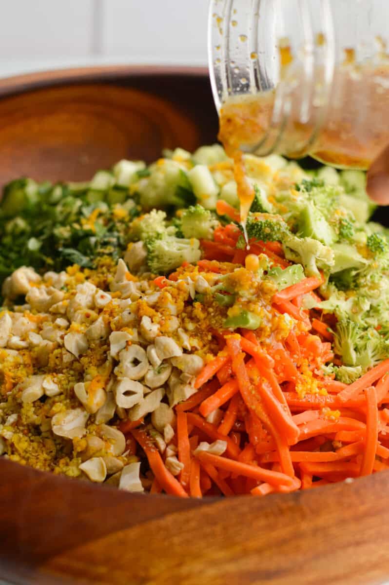 Drizzling orange salad dressing on salad.