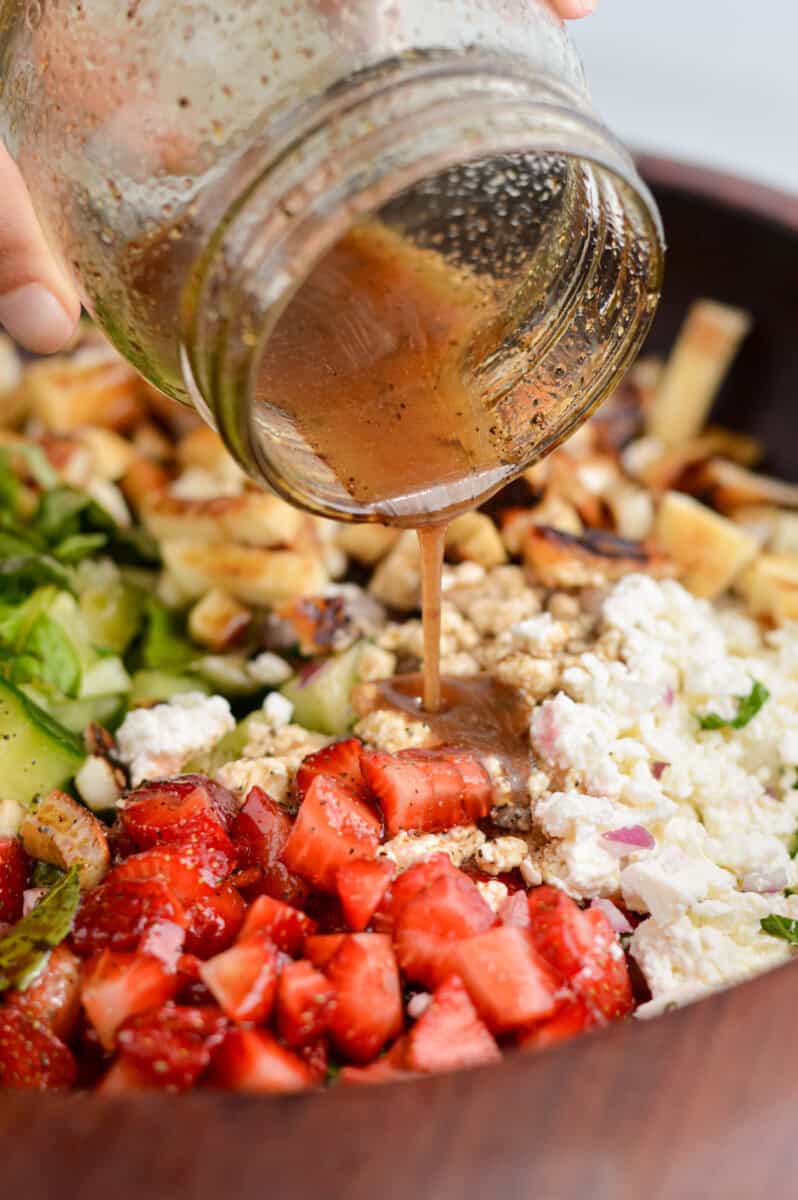Pouring balsamic dressing over salad.