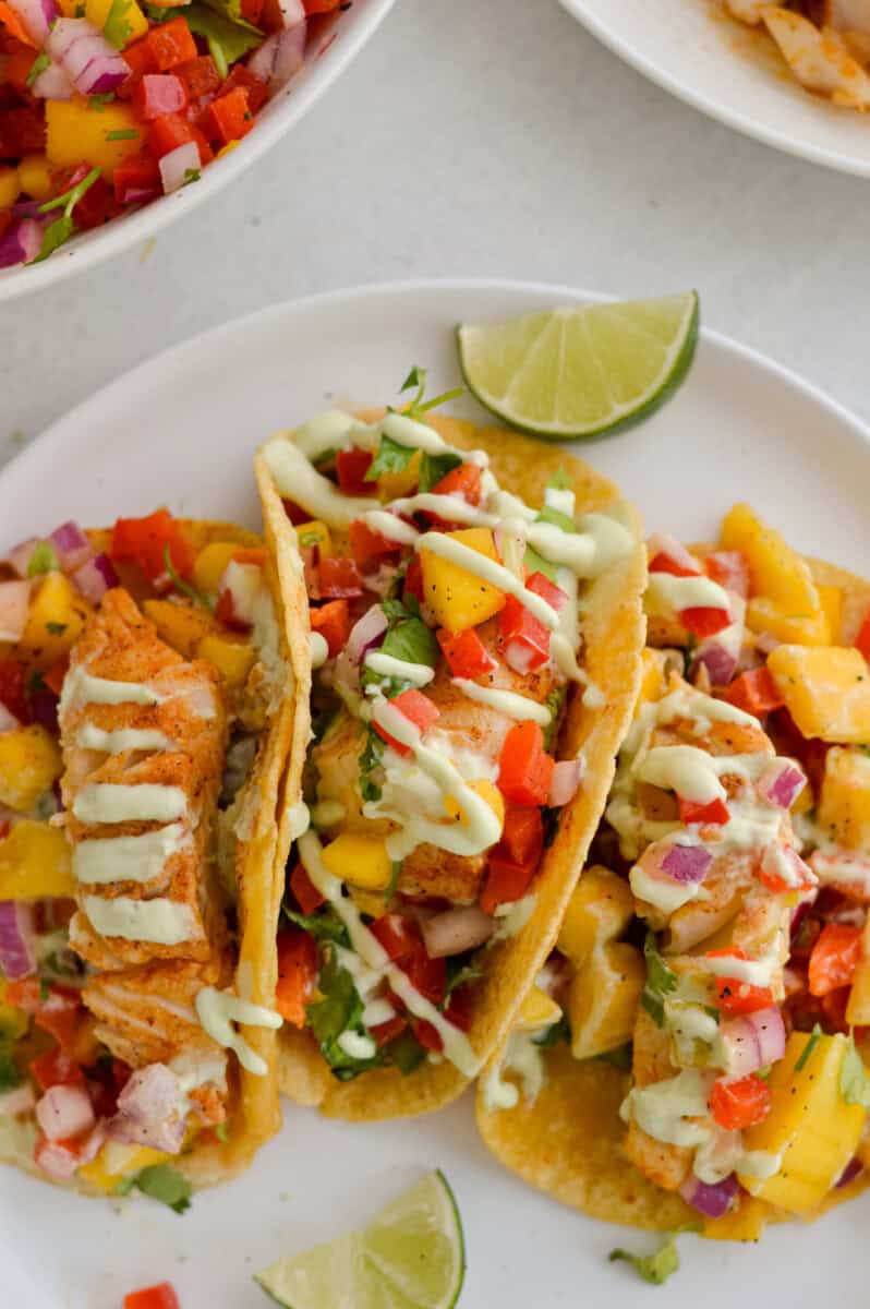 Birds eye of three fish tacos with mango sauce, served with avocado lime crema on top.