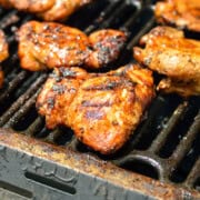 Grilling boneless chicken thighs on a barbecue.