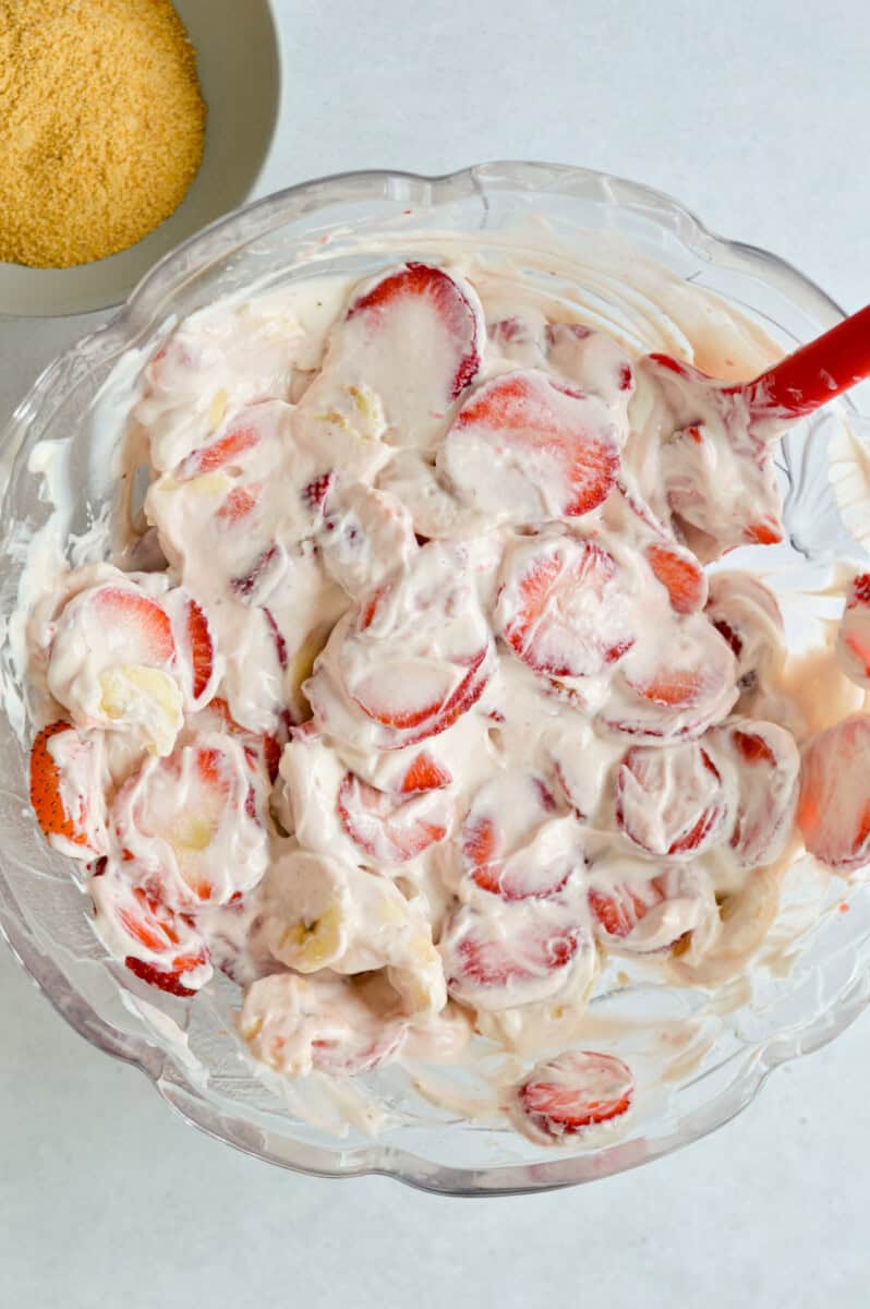 Mixing strawberries and bananas into yogurt base.