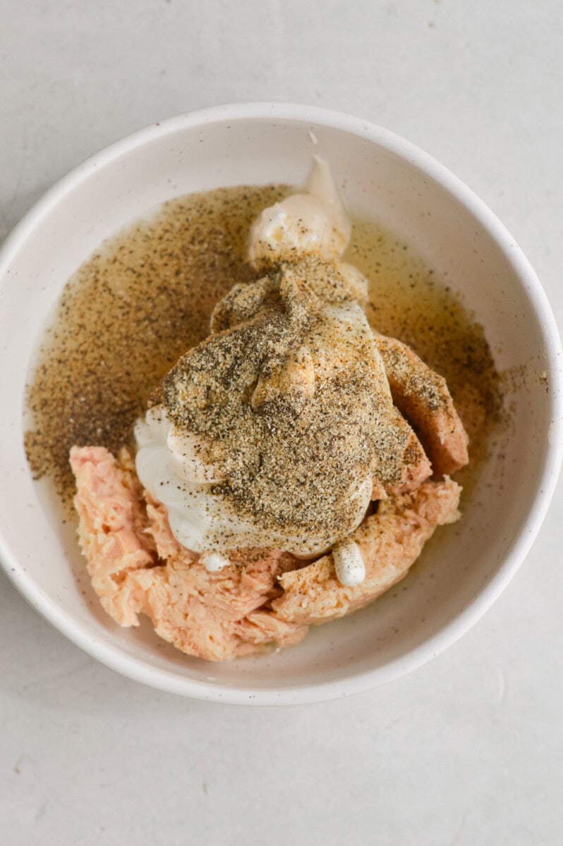 Adding  tuna, greek yogurt, mayonnaise , black pepper, onion powder, garlic powder and pickle juice to a bowl.