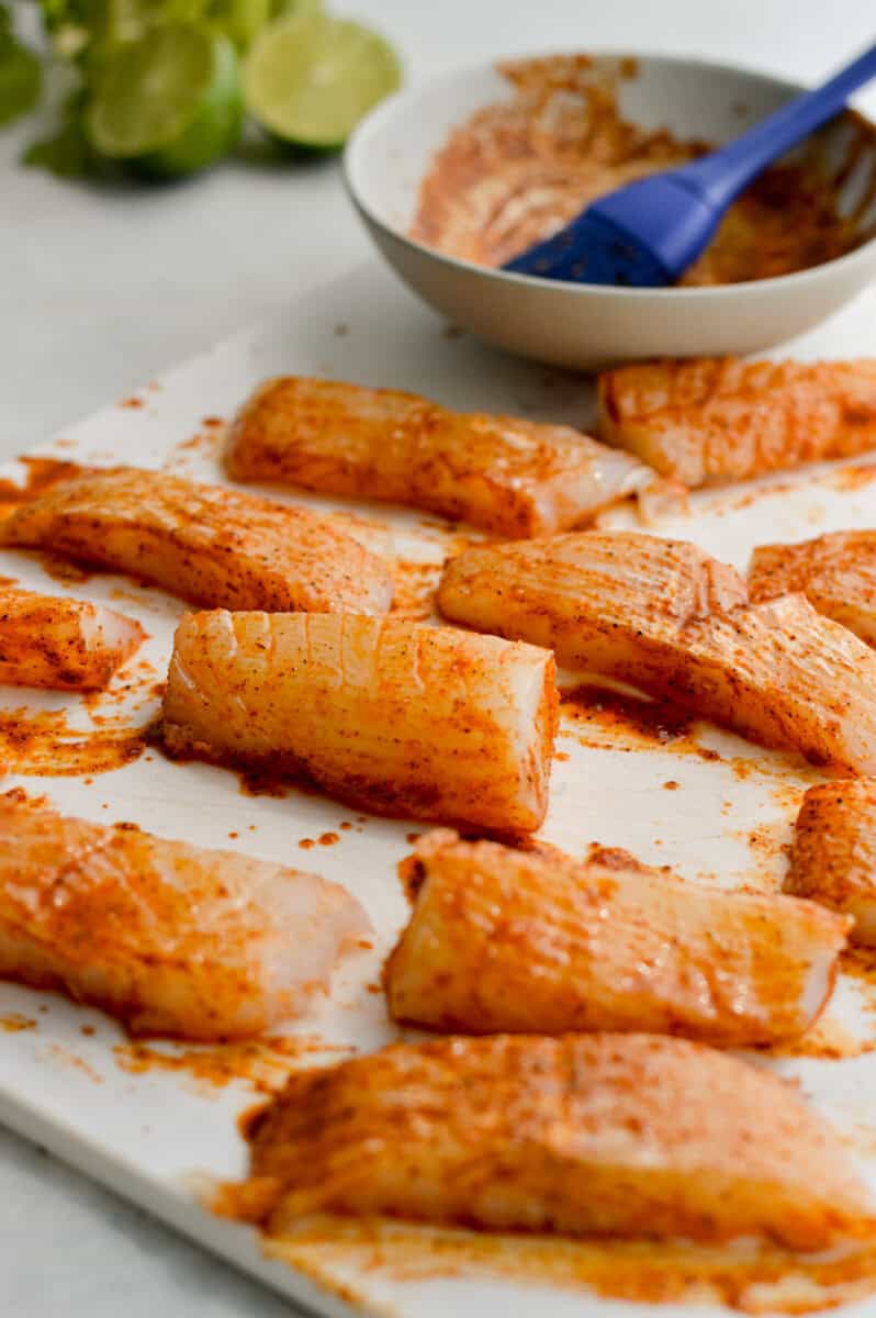 Brushing fish with seasoning and olive oil.