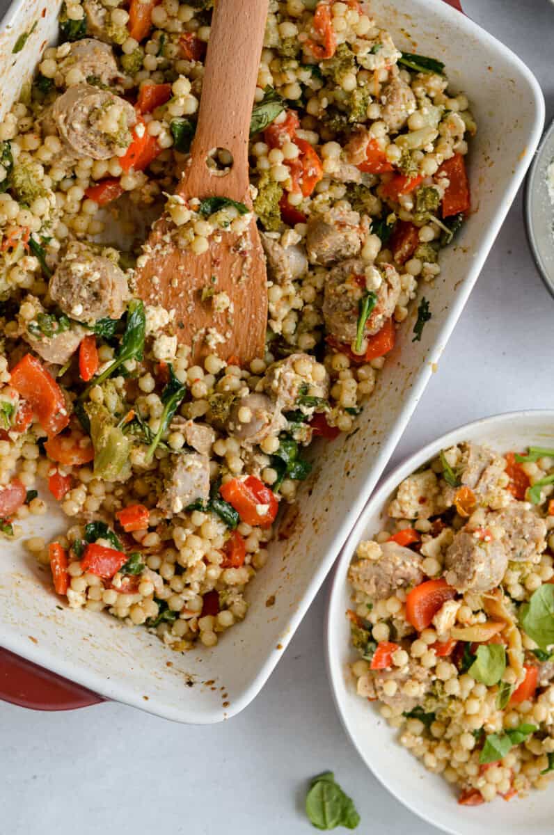 Serving baked feta and sausage couscous into a bowl.