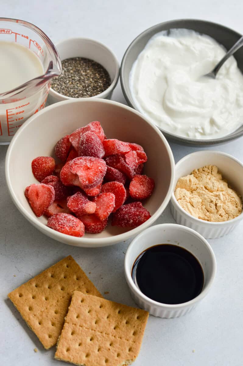 Ingredients including Greek yogurt, berries, graham crackers, maple syrup, protein powder, chia pudding.