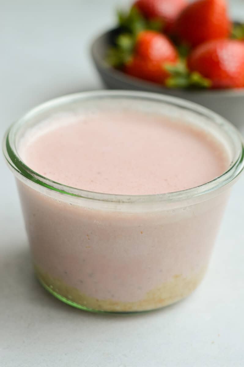 Pouring berry chia pudding into a jar.
