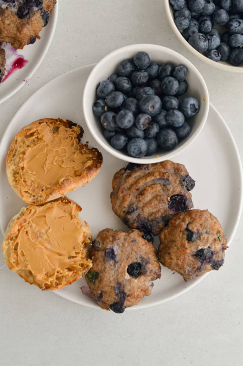 Breakfast plate with peanut butter english muffin, blueberries and sausage patties.