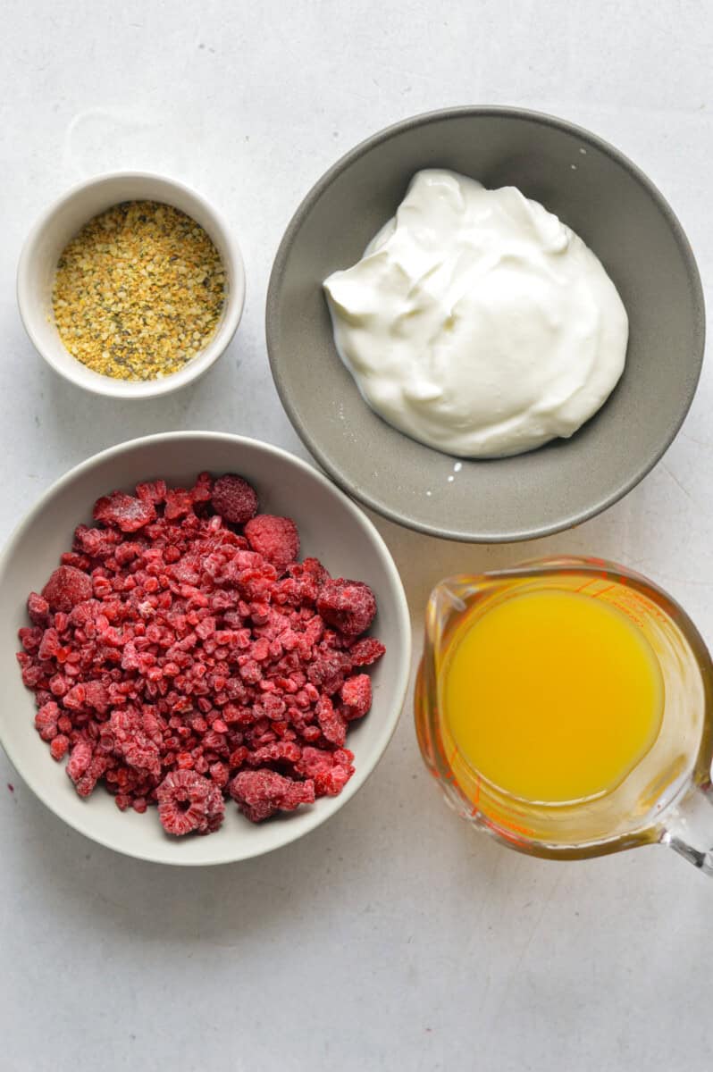 Ingredients including orange juice, frozen raspberries, seed mix and Greek yogurt.