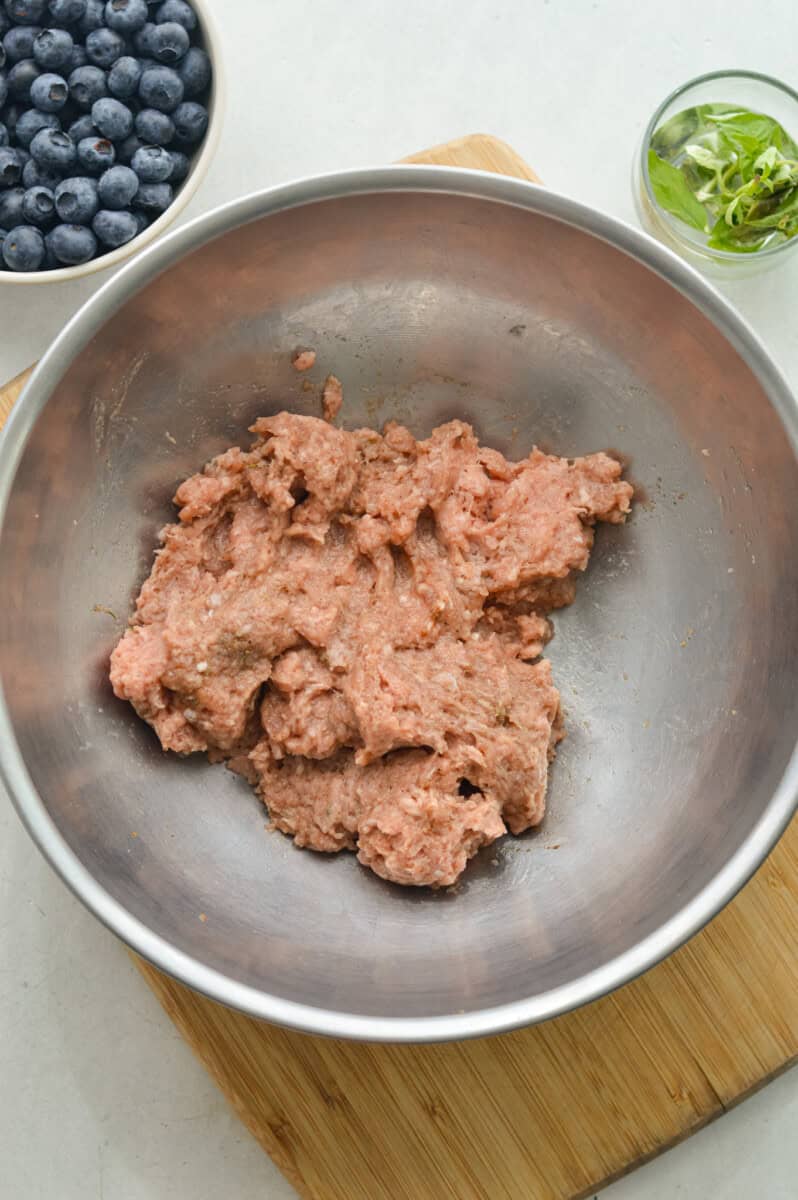 Mixing ground turkey, spices, maple syrup and fresh basil
