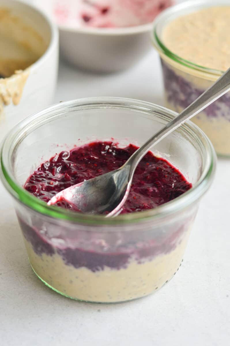 Layering peanut butter oats and chia jam in a jar.