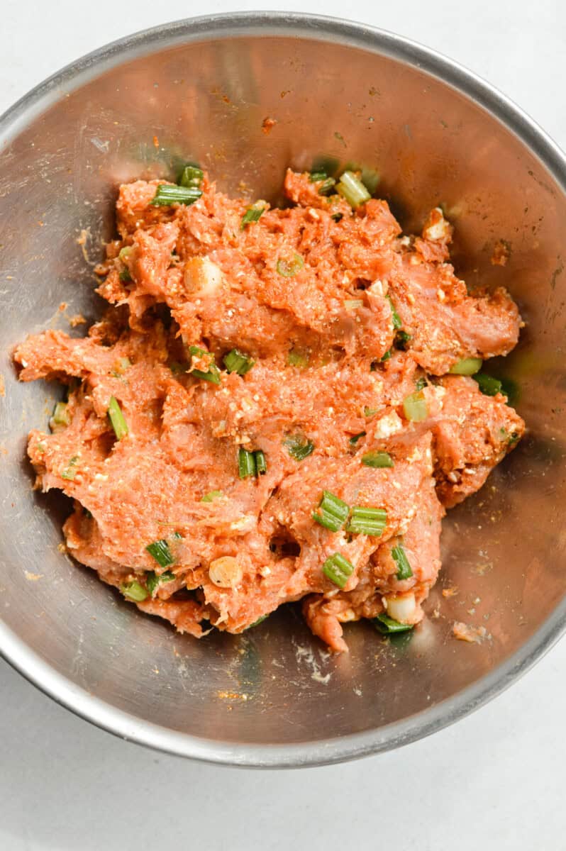Mixing together chicken burgers.