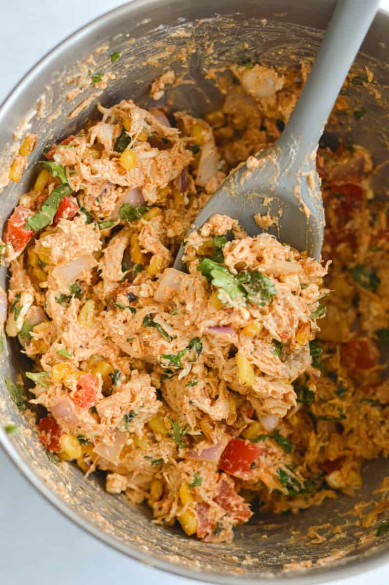 Mixing together Mexican chicken salad.