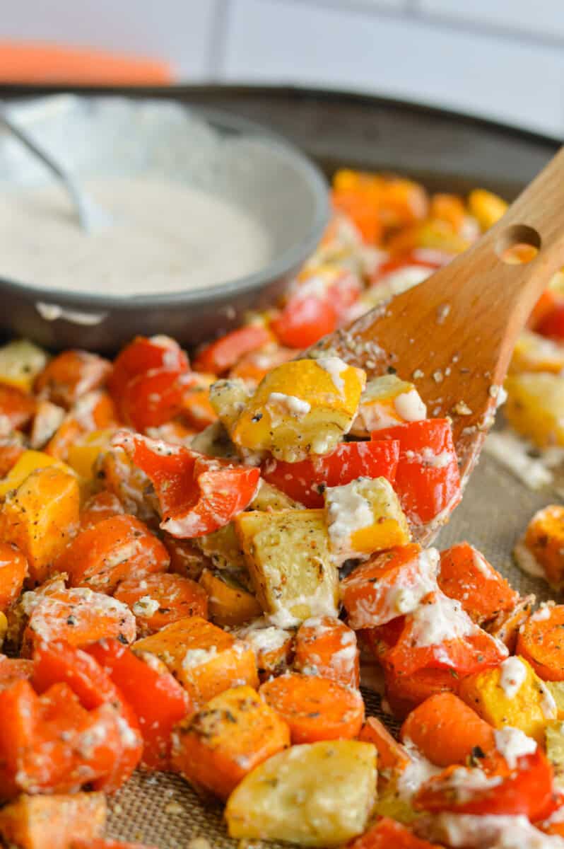Close up of scoopng perfect roasted veggies and bowl of honey mustard sauce.