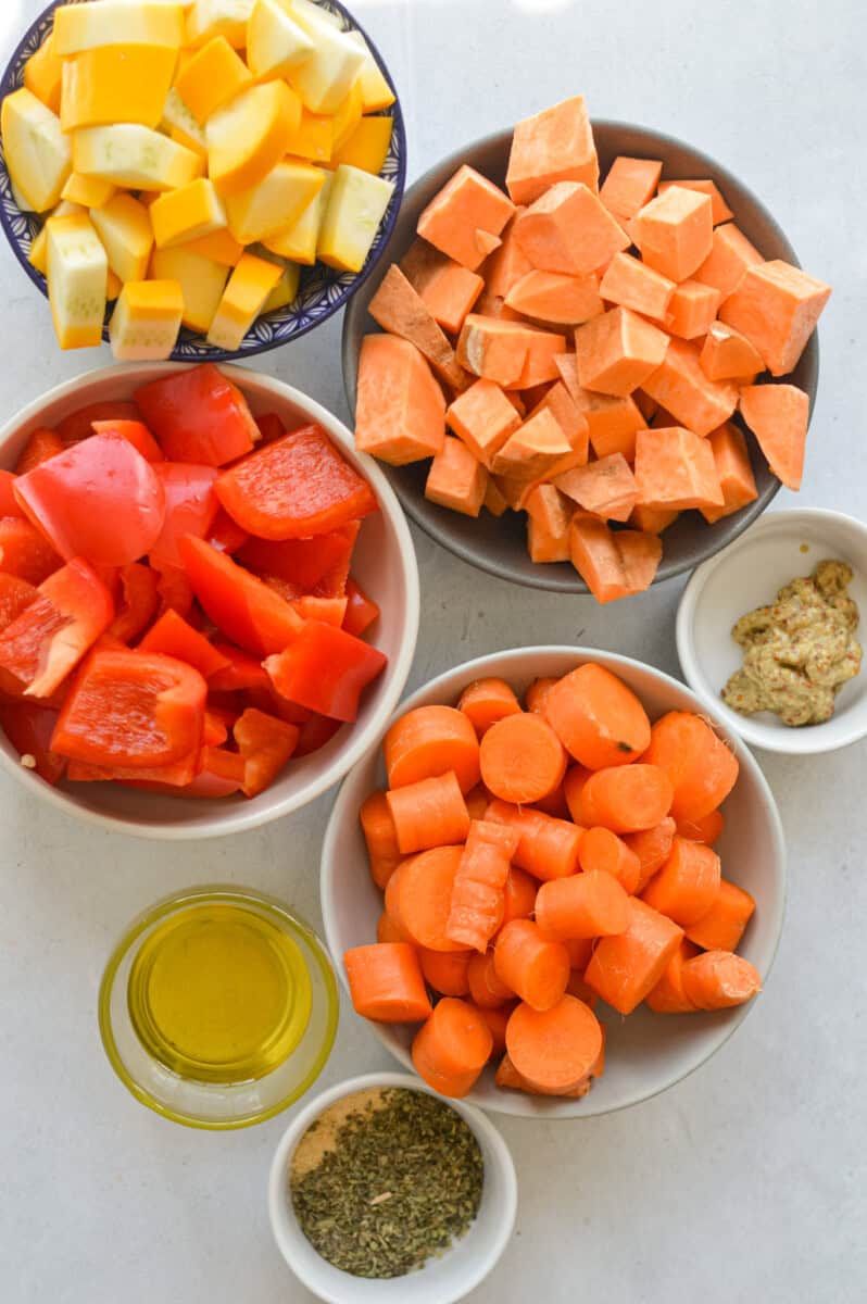 Ingredients including sweet potatoes, carrots, yellow zucchini, red peppers, olive oil and spices.