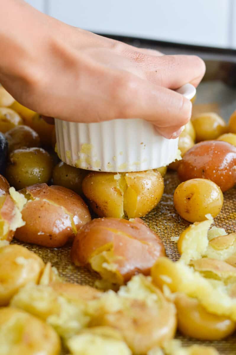 Smashing baby potatoes with the bottom of a ramekin.