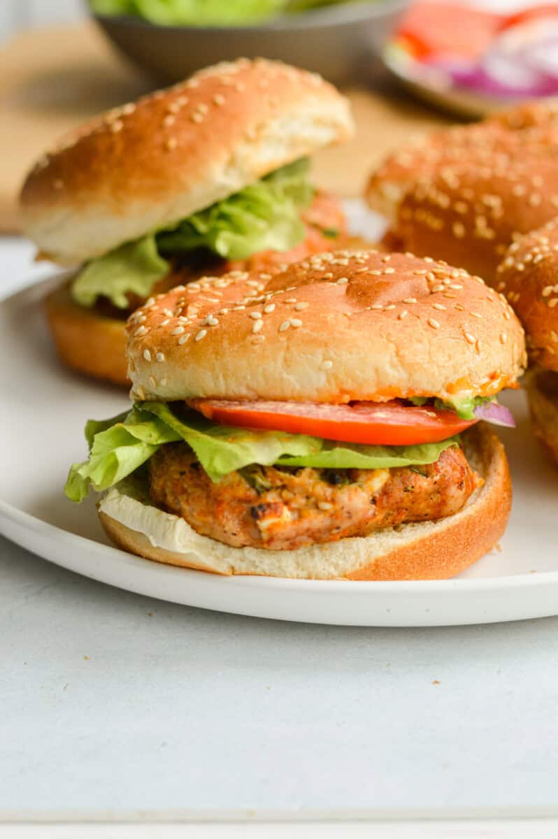 Close up of spicy chicken burger on a bun with tomato and lettuce.