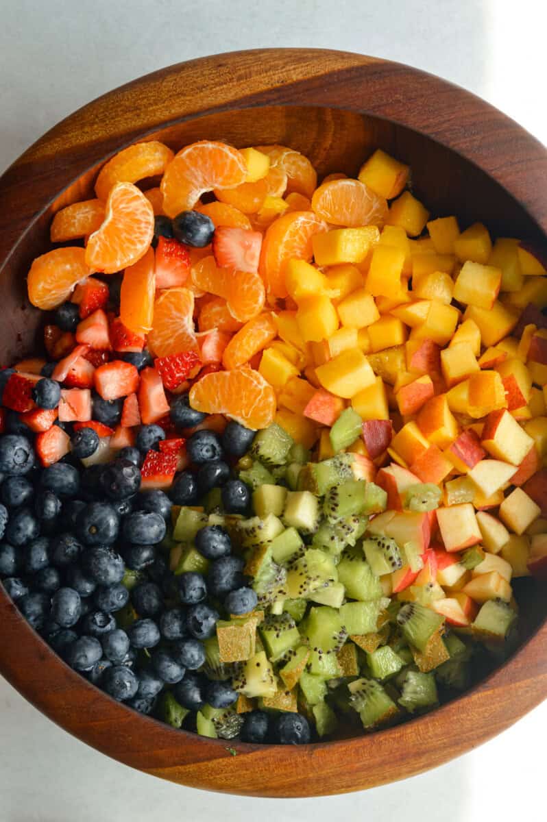 Unmixed fruit salad with oranges, peaches, apple, kiwi, blueberries and strawberries.