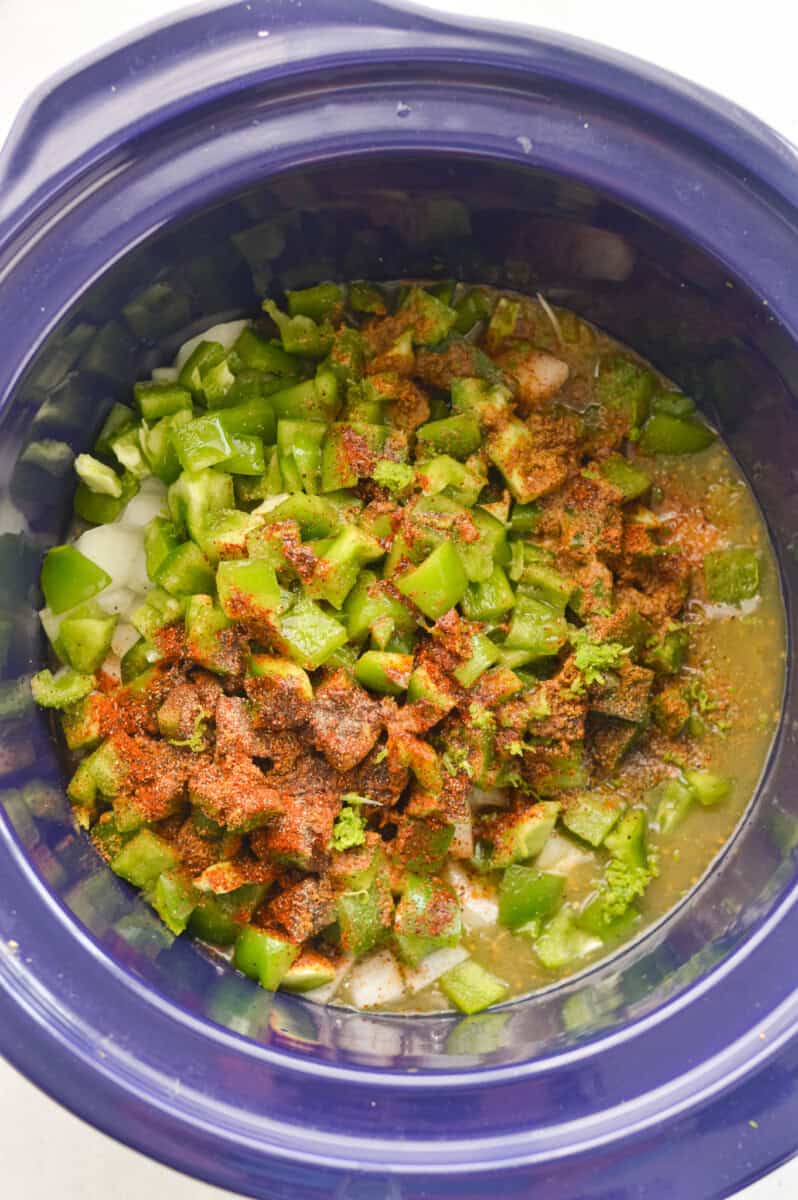 Adding onion, bell pepper, garlic, cumin, chili powder, salt, black pepper, green chilies (and their juices), salsa verde, lime zest and juice of 2 limes to a crockpot.